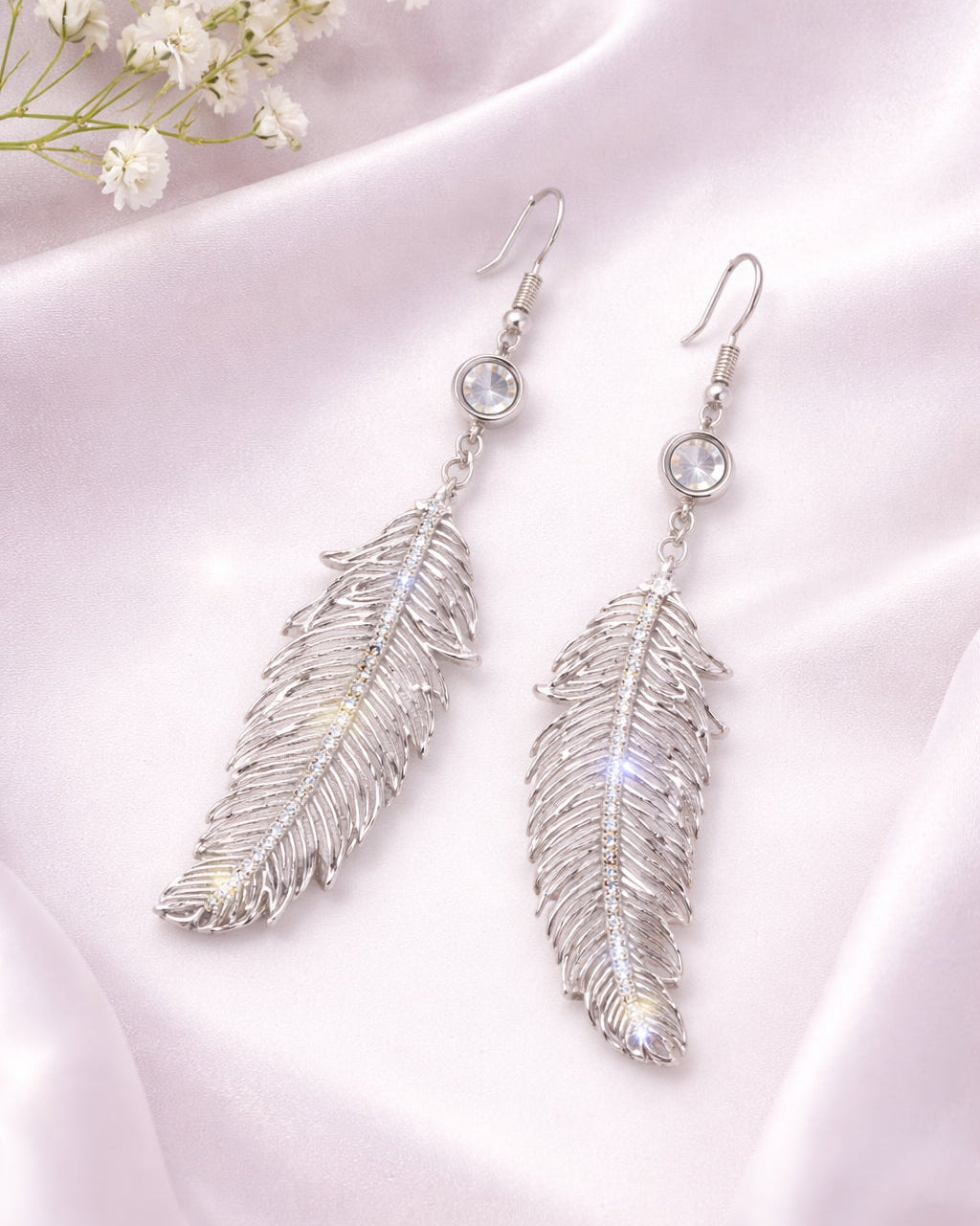 Silver feather-shaped earrings on a white background